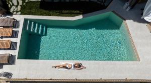 a woman laying down in a swimming pool at Geroulios Kastro I & II, a Grand Estate, By ThinkVilla in Vatoudhiáris