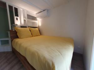 ein kleines Schlafzimmer mit einem Bett mit gelben Kissen in der Unterkunft Le Pigeonnier in Flaujac-Poujols