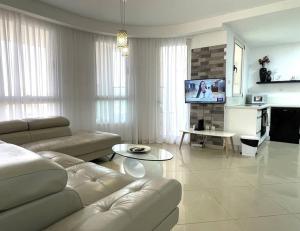 - un salon avec un canapé et une télévision dans l'établissement TRENDY 2BR GOLF RESIDENCE EILAT, à Eilat