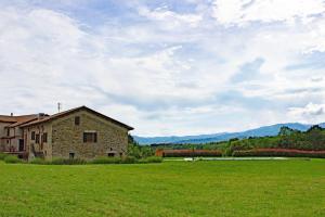 a stone building in a field next to a grass field at Locanda Fermento in Mochignano