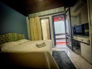 a bedroom with a bed and a tv and a television at Hospedagem Vida e Natureza in Gramado