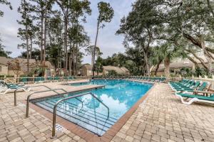 a swimming pool with blue chairs and trees at Heritage Villas 2307 in Hilton Head Island