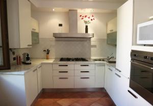 a kitchen with white cabinets and a stove top oven at Civico 24 in Cremona