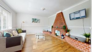 a living room with a couch and a brick fireplace at Stunning 3-Bed House in Basildon in Basildon