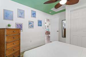- une chambre avec un lit, une commode et un ventilateur de plafond dans l'établissement Pink Flamingo, à Dunedin