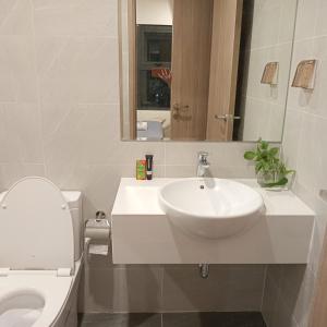 uma casa de banho branca com um lavatório e um WC em FThomestay at Vinhome Grand Park HCM em Gò Công