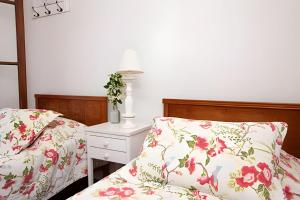 1 dormitorio con 2 camas con almohadas florales y mesita de noche en Fazenda Santa Teresa de 1 a 30 pessoas en Bocaina