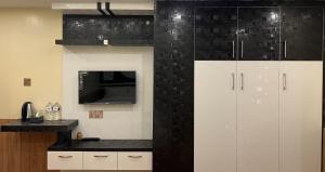 a kitchen with white cabinets and a black tile wall at Pine Tree Resort in Bhaktapur