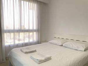 - un lit blanc avec 2 serviettes dans l'établissement TRENDY 2BR GOLF RESIDENCE EILAT, à Eilat