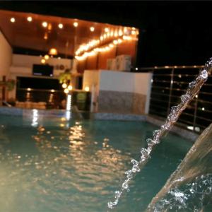 uma fonte de água numa piscina à noite em HOTEL AMERICANO em Jaén