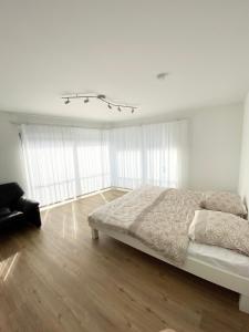 ein weißes Schlafzimmer mit einem Bett und einem Kronleuchter in der Unterkunft Modern One Bedroom + Bathroom Apartment, 10 min from Basel City in Grenzach-Wyhlen + 5 Fotos