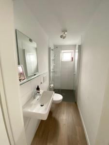 a white bathroom with a sink and a mirror at Modern One Bedroom + Bathroom Apartment, 10 min from Basel City in Grenzach-Wyhlen