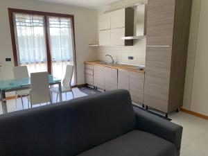 Il comprend un salon avec un canapé et une cuisine avec une table. dans l'établissement Damo Stefania Blu Hause Marina, à Cavallino-Treporti
