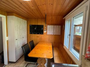 ein Esszimmer mit einem Holztisch und einem Fenster in der Unterkunft See und Berge Family in Faulensee