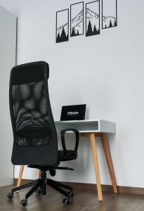 a black chair sitting next to a desk with a laptop at HiRooms Brașov in Braşov
