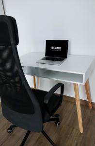 a desk with a laptop and a black chair at HiRooms Brașov in Braşov