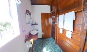 a bathroom with a toilet and a wooden door at Hotel Ecolodge Riake Resort & Villa in Sainte Marie