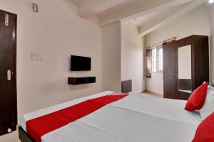 a white bedroom with a bed with a red blanket at OYO Flagship 81553 Green Residency in Bangalore