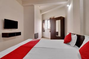 een slaapkamer met een groot wit bed en een rode deken bij OYO Flagship 81553 Green Residency in Bangalore