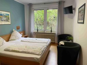 a bedroom with a bed and a chair and a window at Pension Bartz in Traben-Trarbach