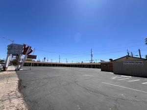 een lege parkeerplaats met een bord en een gebouw bij Border Motel in Calexico