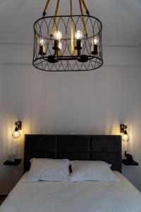 a chandelier hanging over a bed with a white bedspread at Ophelia - New Modern Apartment with Spectacular Olympus View in Litochoro