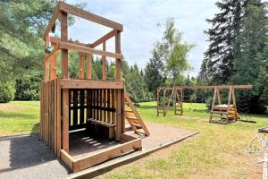 um parque infantil de madeira com dois baloiços num parque em Le1613 - Bord de l'eau - Les chalets dans le nord em Val-David