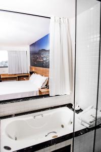 a bathroom with a large mirror and a bath tub at Trade Hotel in Juiz de Fora