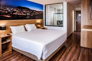 Trade Hotel في جويز دي فورا: غرفة نوم بسرير ابيض كبير ولوحة على الحائط