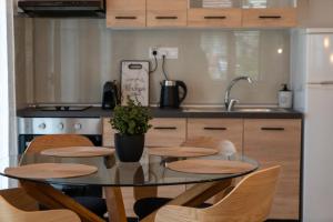 cocina con mesa de cristal con sillas y fregadero en Ophelia - New Modern Apartment with Spectacular Olympus View, en Litóchoron
