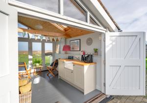 a barn door opens up to a kitchen with a table at Dolphin Cottage - Brancaster Staithe in Brancaster