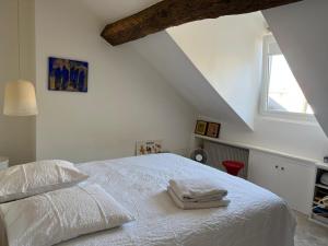a bedroom with a white bed with two towels on it at Appartement Versailles 5 mn à pied château et gare Versailles Rive Gauche Château in Versailles