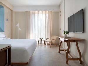 1 dormitorio con 1 cama, escritorio y TV en Kimpton Las Mercedes, an IHG Hotel, en Santo Domingo