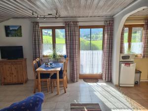 een woonkamer met een tafel, stoelen en ramen bij Bei Schneider's in Ruhpolding