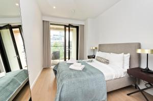 a bedroom with a large bed and a balcony at Elegant and Modern Apartments in Canary Wharf right next to Thames in London