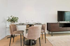 comedor con mesa con sillas y TV en Elegant and Modern Apartments in Canary Wharf right next to Thames, en Londres