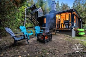 een zwart tiny house met stoelen en een kampvuur bij Le1615 - Lac, Quai privé- Les chalets dans le nord in Val-David
