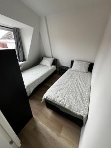 two beds in a small room with white walls at Stays by ADM in Leiden