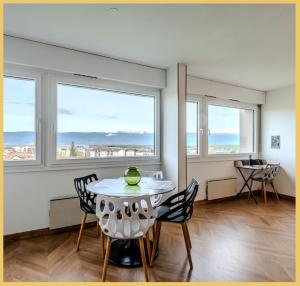 a dining room with a table and chairs and windows at Chez Fan & Alex St Julien in Saint-Julien-en-Genevois