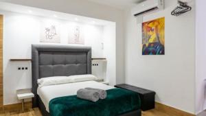 una camera da letto con un grande letto e un pouf verde di Ilustre Rooms by Beehive Vacances a Málaga
