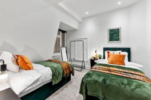 Lovely Penthouse in Worthing - Sleeps 6 في وورثينغ: سريرين في غرفة بجدران بيضاء ووسائد برتقالية