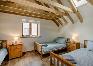 1 dormitorio con 2 camas, ventana y suelo de madera en Barley Barn en Kimberley