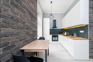 eine Küche mit einem Holztisch und einer Ziegelwand in der Unterkunft Piotrkowska Modern Apartment in Łódź