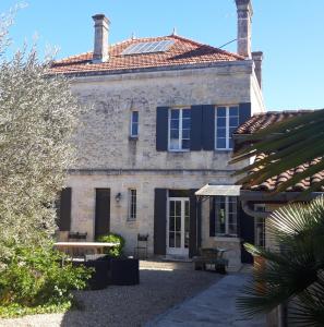 une ancienne maison en pierre avec un toit bleu dans l'établissement Domaine de Quittignan Brillette, à Moulis-en-Médoc