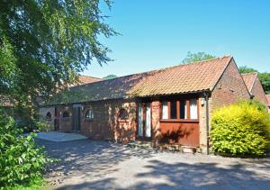 an old brick building with a garage and a driveway at The Stables in Elsing
