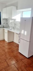 a kitchen with white cabinets and a white refrigerator at Noclegi u Ewusi in Januszowice