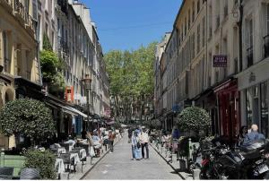 a group of people walking down a city street at Appartement Versailles 5 mn à pied château et gare Versailles Rive Gauche Château in Versailles
