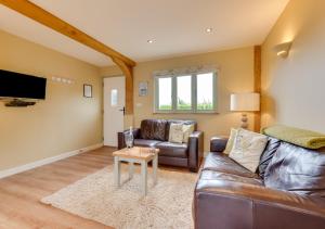 a living room with a leather couch and a table at Partridge Lodge in Reepham