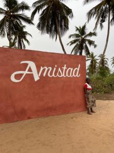 une femme debout devant un panneau sur la plage dans l'établissement Amistad, à Ouidah