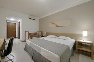 een hotelkamer met een groot bed en een bureau bij Garden Hotel in Ribeirão Preto